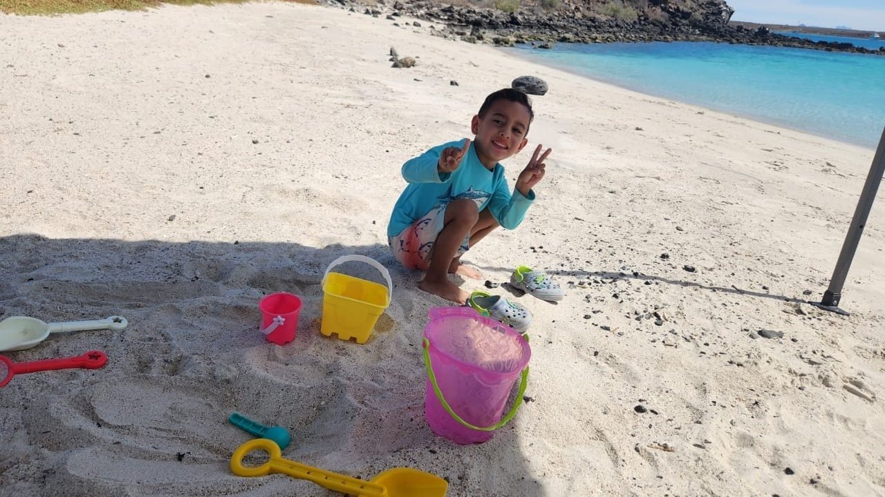Una niña hace castillos de arena con cubetas de colores en la playa blanca de Isla Coronado, Loreto